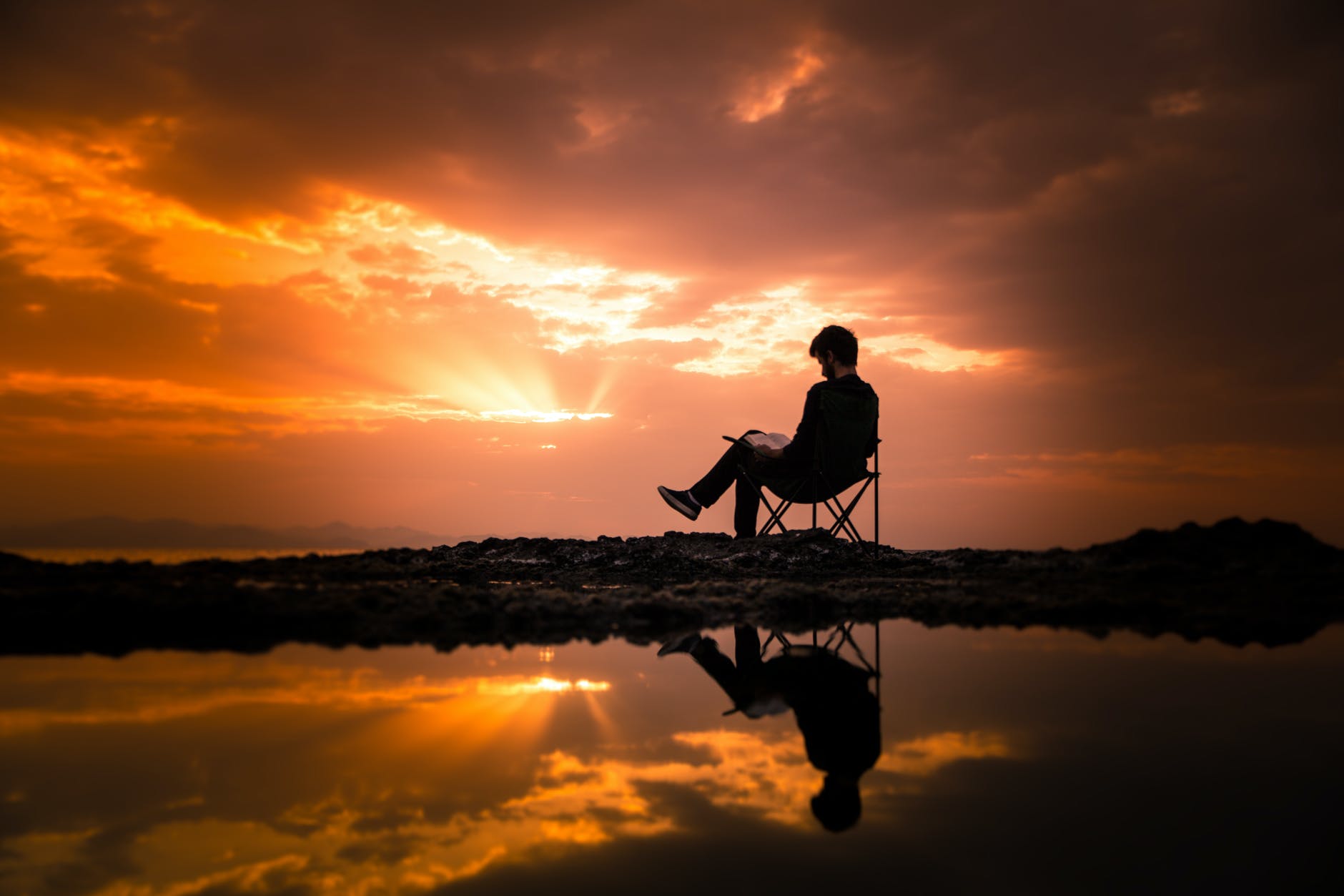 photo of man sitting on camping chair during dawn